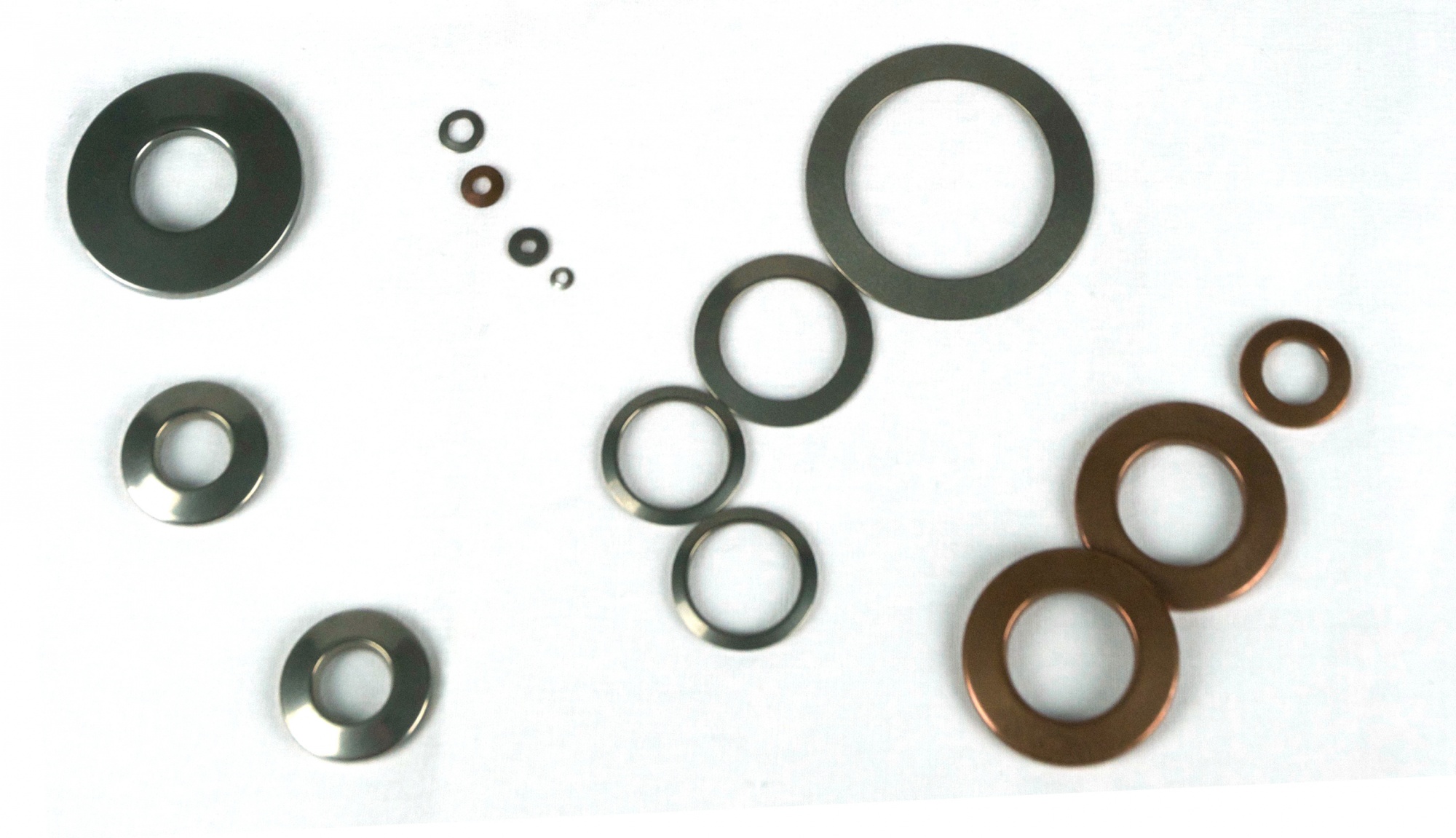 A collection of washers of various shapes and sizes on a white table